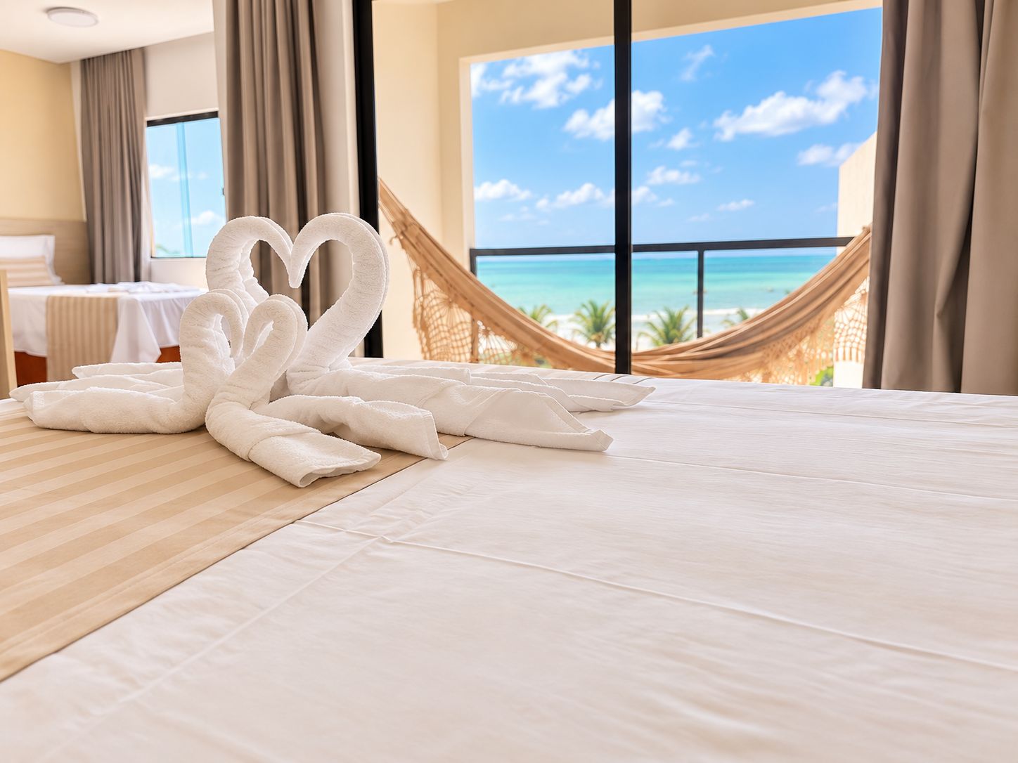 A hotel room with a bed, a hammock, and a view of the ocean.