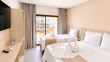 Ein Hotelzimmer mit zwei Betten, einem Fernseher, einem Schreibtisch und Blick ins Freie.
