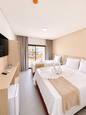 A hotel room with two beds, a TV, a desk, and a view of the outside.