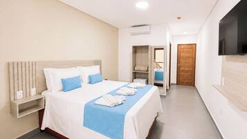 Una habitación de hotel con cama, armario, televisor y puerta.