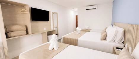 A hotel room with two beds, a TV, a wardrobe, and a mirror.