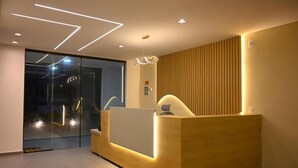 Uma receção com design moderno, entrada por porta de vidro e parede revestida a madeira.