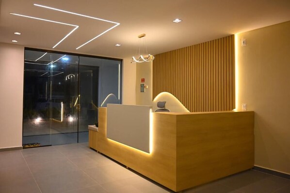 A reception desk with a modern design, a glass door entrance, and a wooden panel wall.