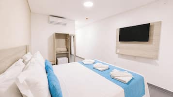 Una habitación de hotel con cama, armario, televisor y aire acondicionado.