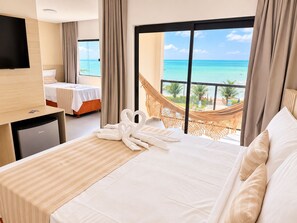 Una habitación de hotel con una cama, escritorio, televisión y vista al océano.