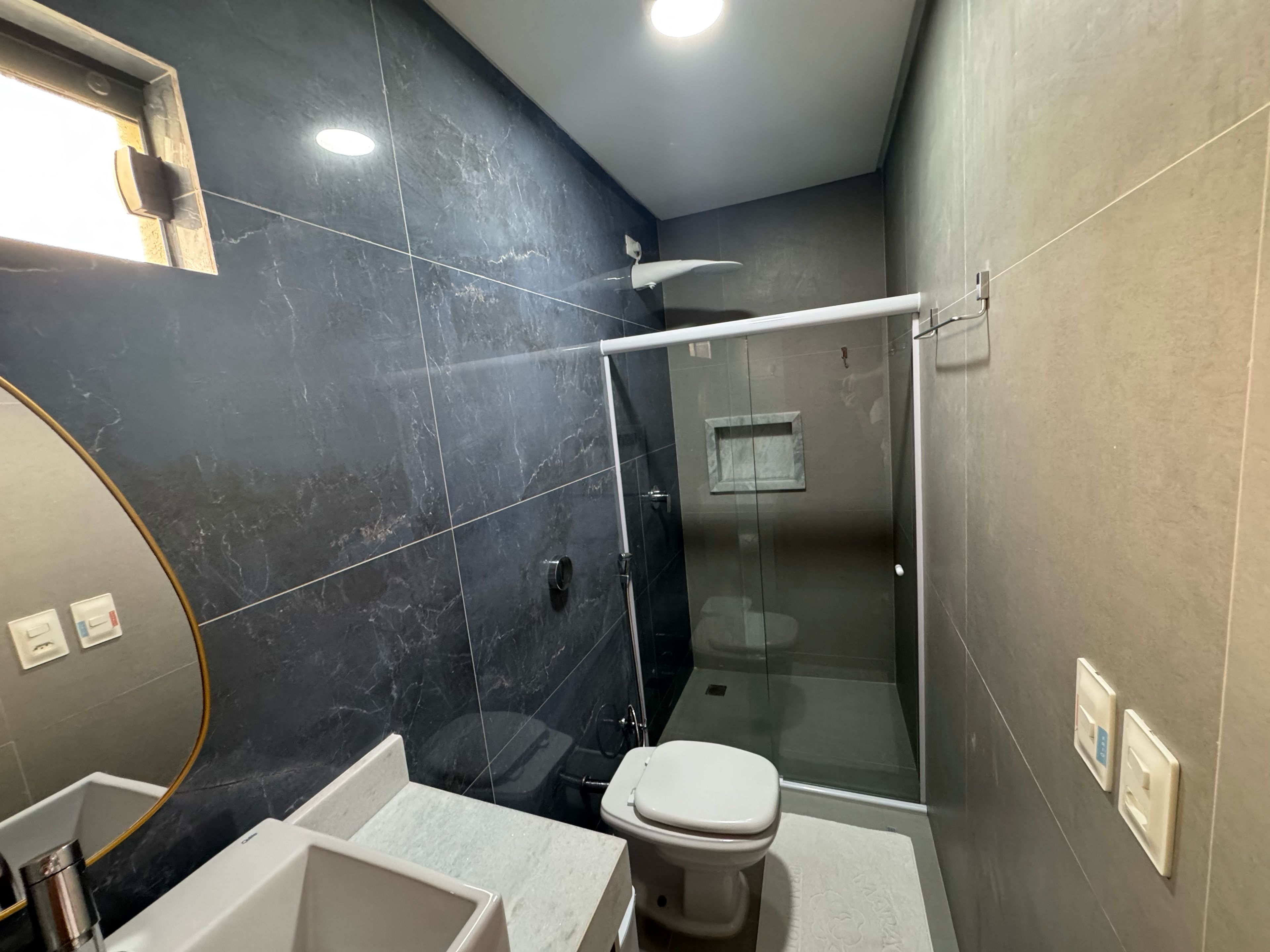 Un baño moderno con ducha de vidrio, inodoro blanco y un espejo grande.