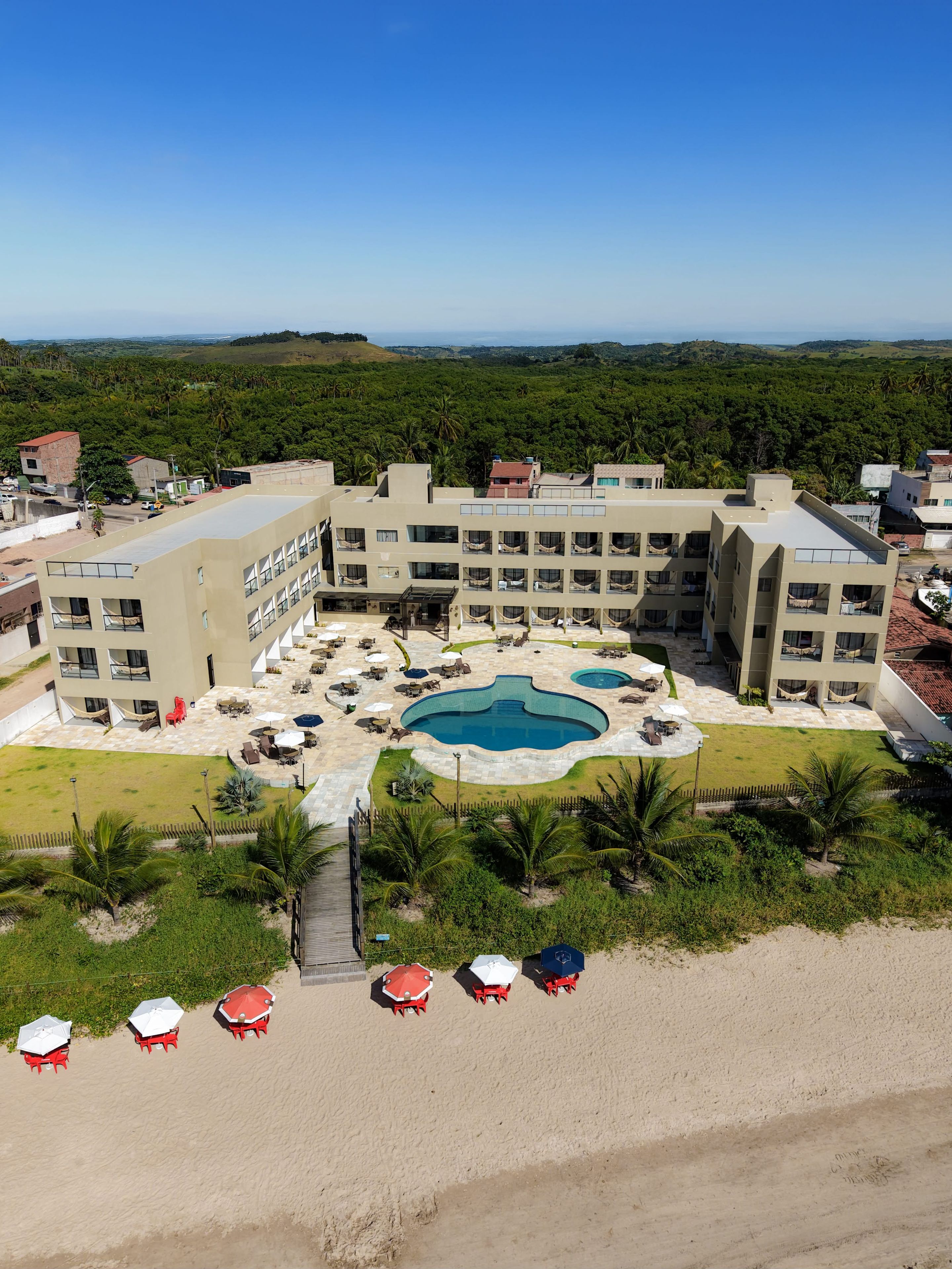 A hotel with multiple floors, a central swimming pool, and outdoor seating areas.