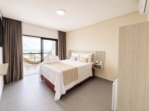 A hotel room with a large bed, a nightstand, a view of the ocean, and a hammock.