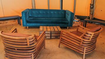 Ein Zimmer mit einem blauen Sofa, Holzstühlen, einem Couchtisch und einem gemusterten Teppich.