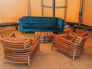 A room with a blue sofa, wooden chairs, a coffee table, and a patterned rug. - Firefly Cottage (Cirencester)