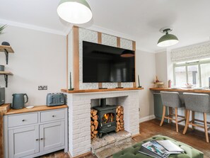 Una cocina moderna con chimenea, un televisor de pantalla plana y un comedor con taburetes de bar.