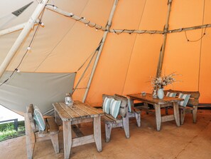 A tent with a table and benches, a vase with flowers, and a bottle on the table. - Firefly Cottage (Cirencester)
