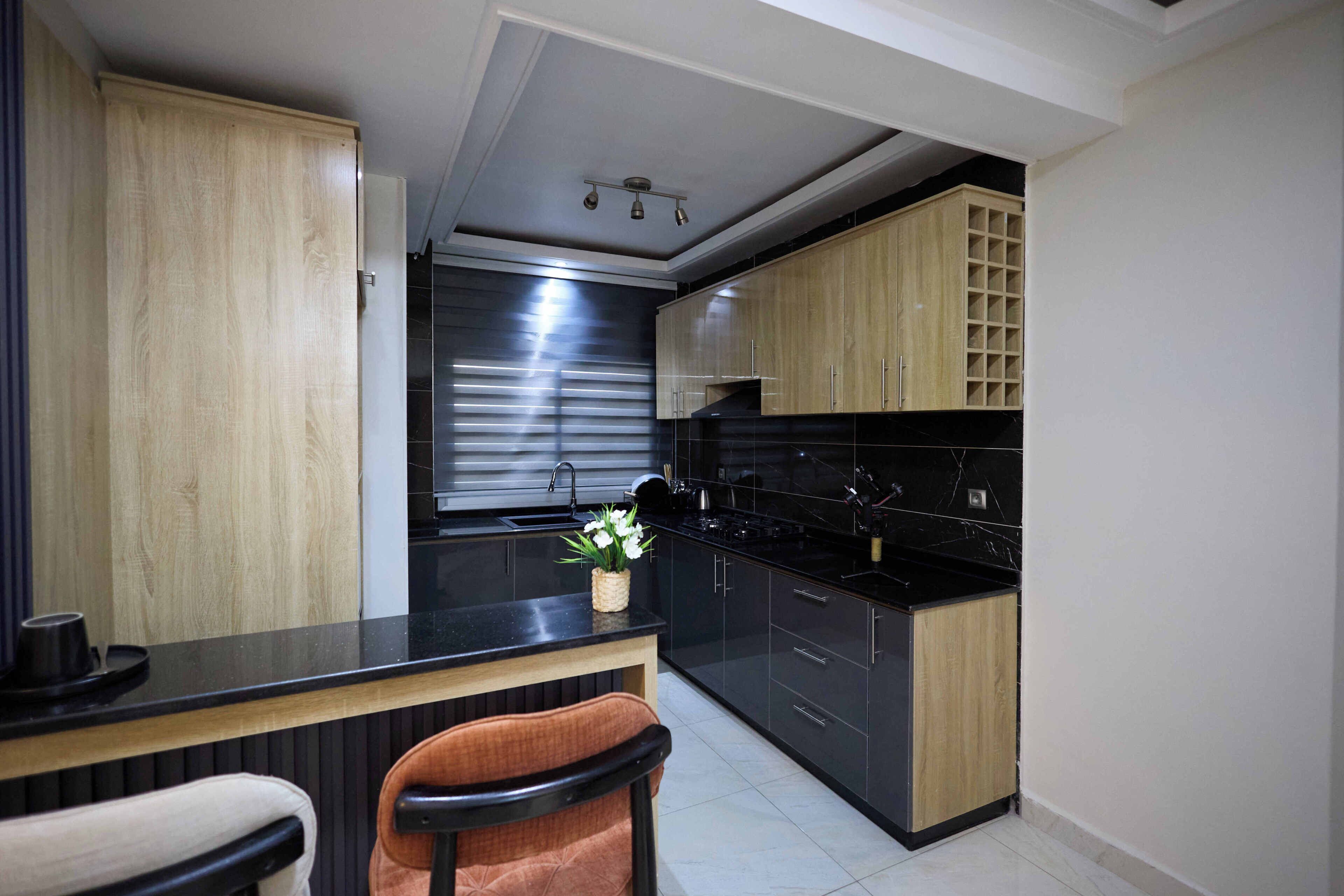 A modern kitchen with black countertops, wooden cabinets, and a built-in stove.