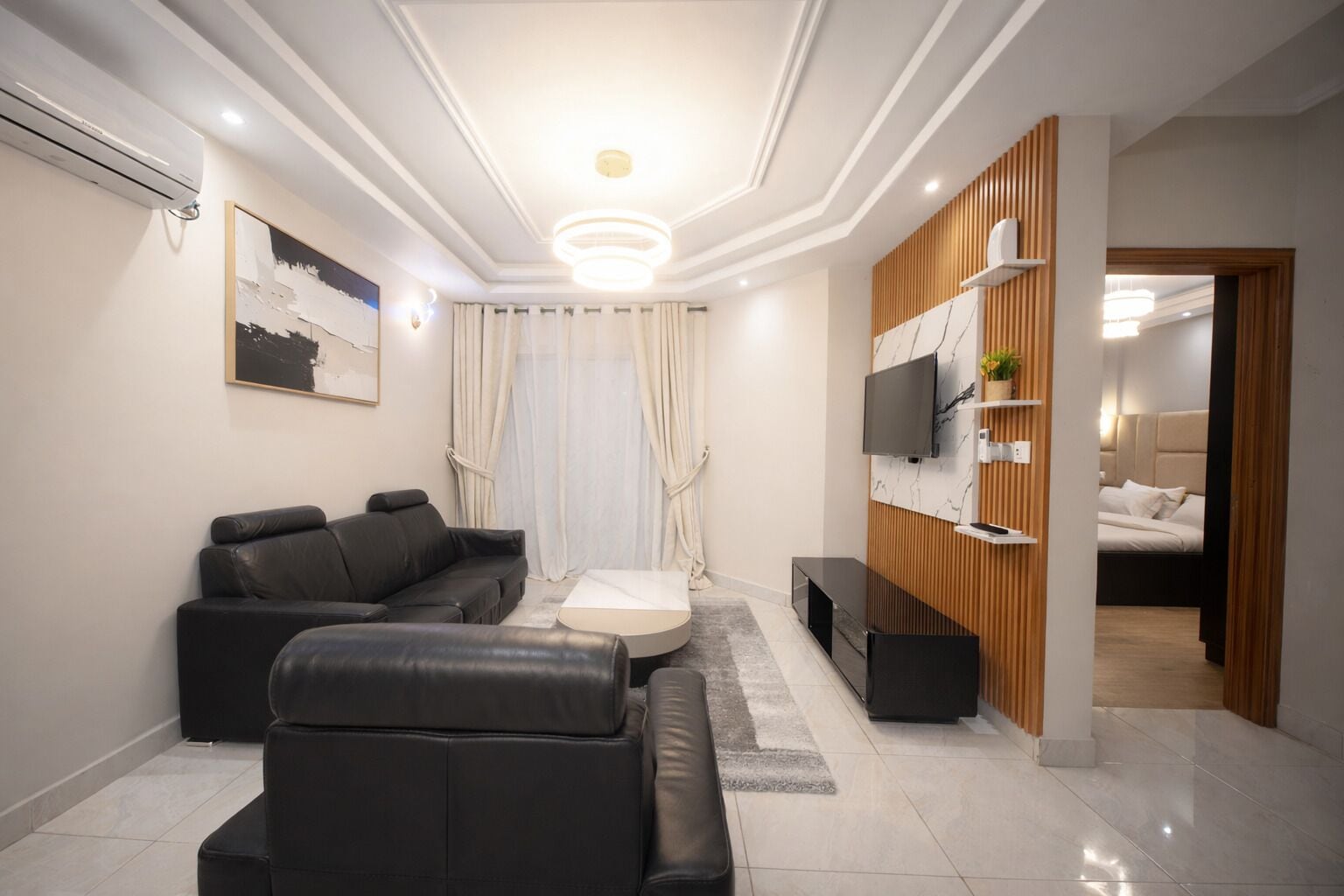 Uma sala de estar moderna com sofá, mesa de centro, TV e uma parede de destaque em madeira.