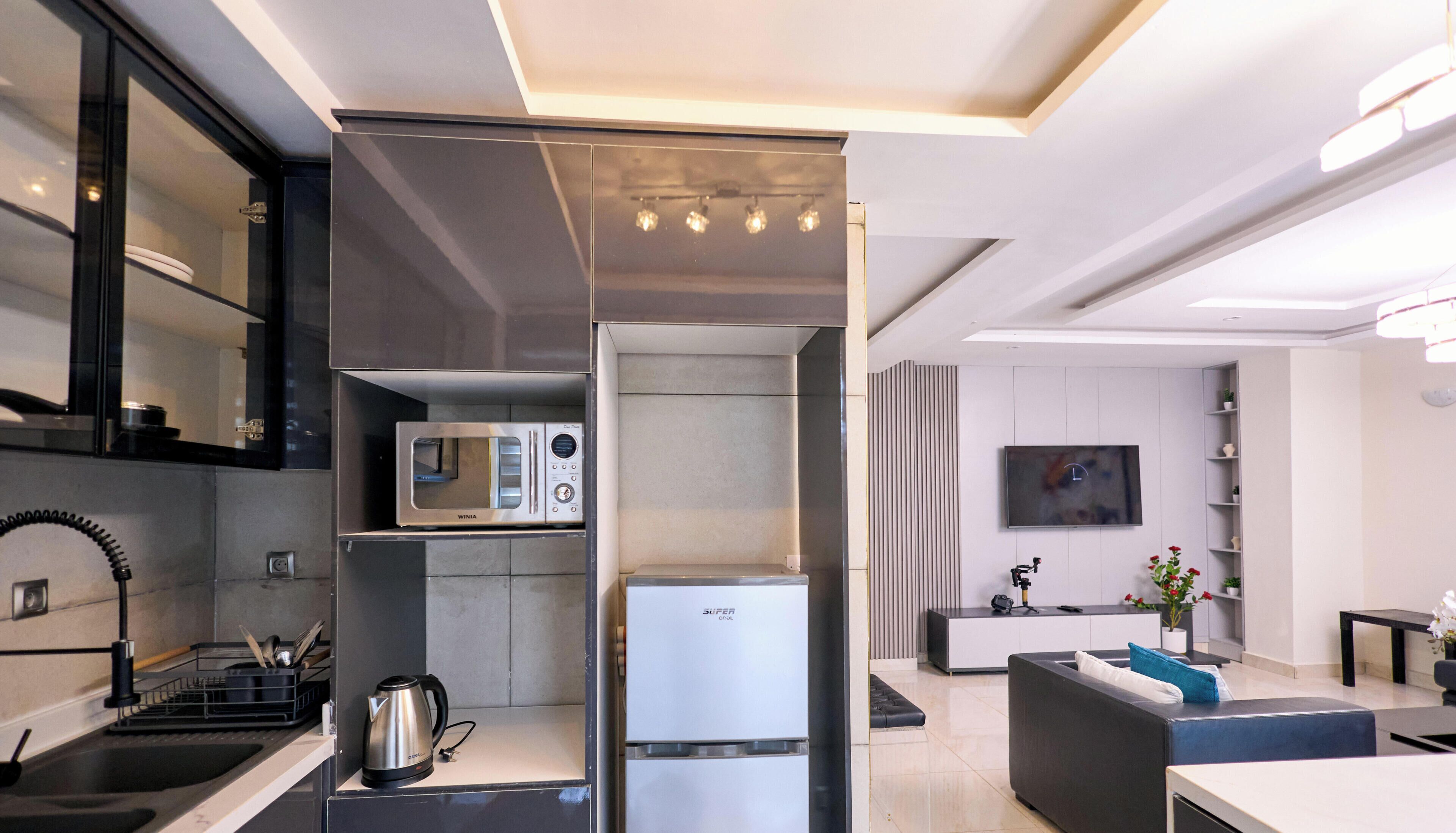 A modern kitchen with built-in appliances, a flat-screen TV, and a seating area.
