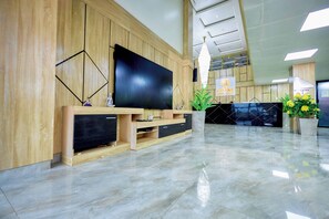 Eine moderne Lobby mit großem Flachbildfernseher, Holzverkleidung, einer Rezeption und einem polierten Marmorboden.