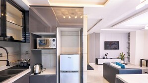 Une cuisine moderne équipée d’un four à micro-ondes encastré, d’un réfrigérateur et d’une bouilloire posée sur le plan de travail.