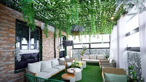 Un espace de détente intérieur accueillant, avec des murs en briques, des plantes artificielles vertes et un mobilier moderne.