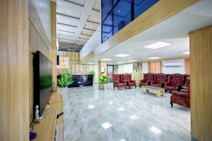 A lobby with a reception desk, seating area, and a TV screen. - EMPIRE LUXURY HOTEL (Yaoundé)
