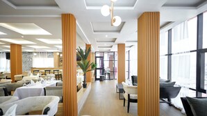 Un hall d’hôtel spacieux, doté de hauts plafonds, de grandes fenêtres et d’un aménagement intérieur moderne.