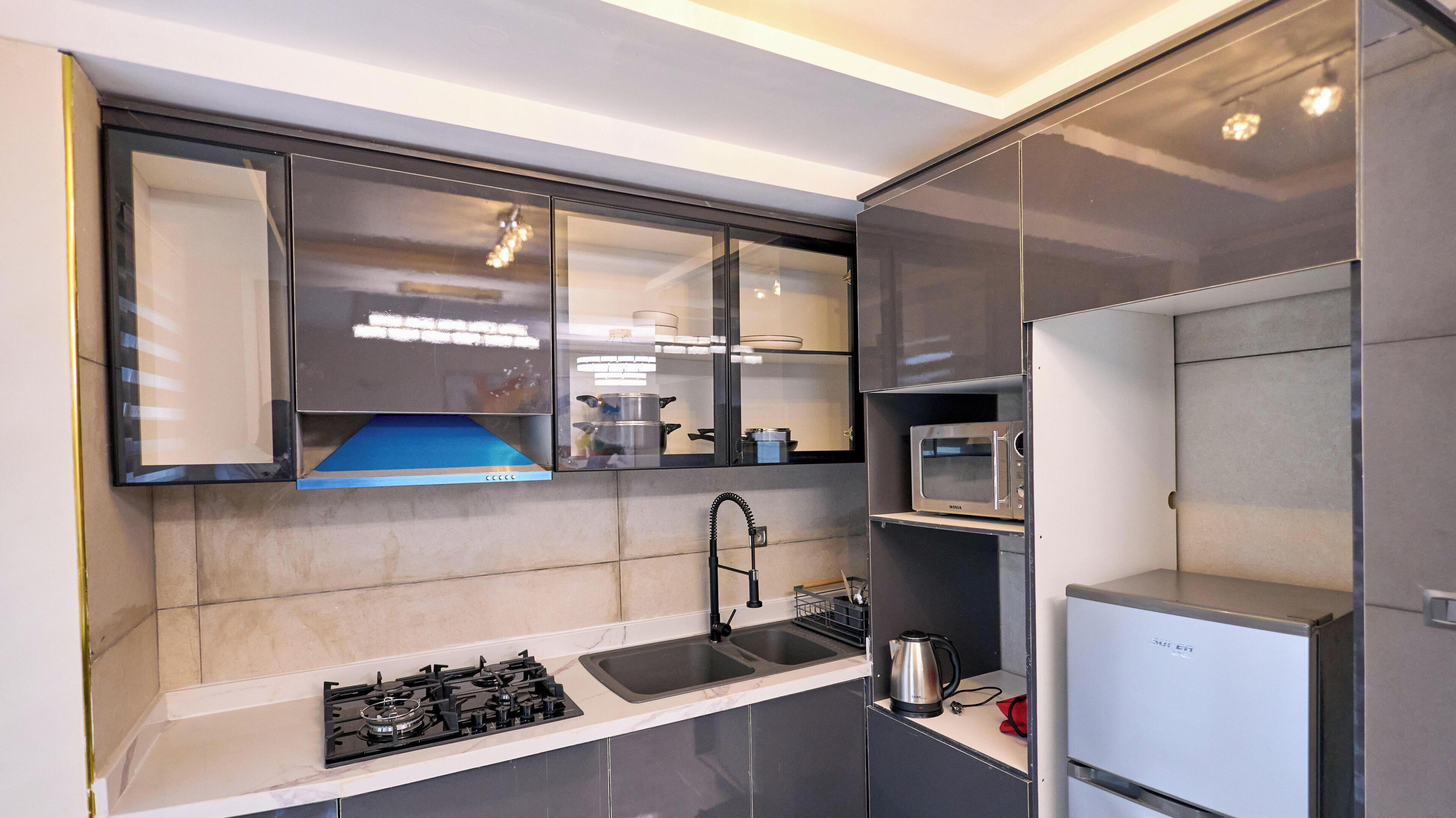 A compact kitchen with a gas stove, a sink, a microwave, and a refrigerator.