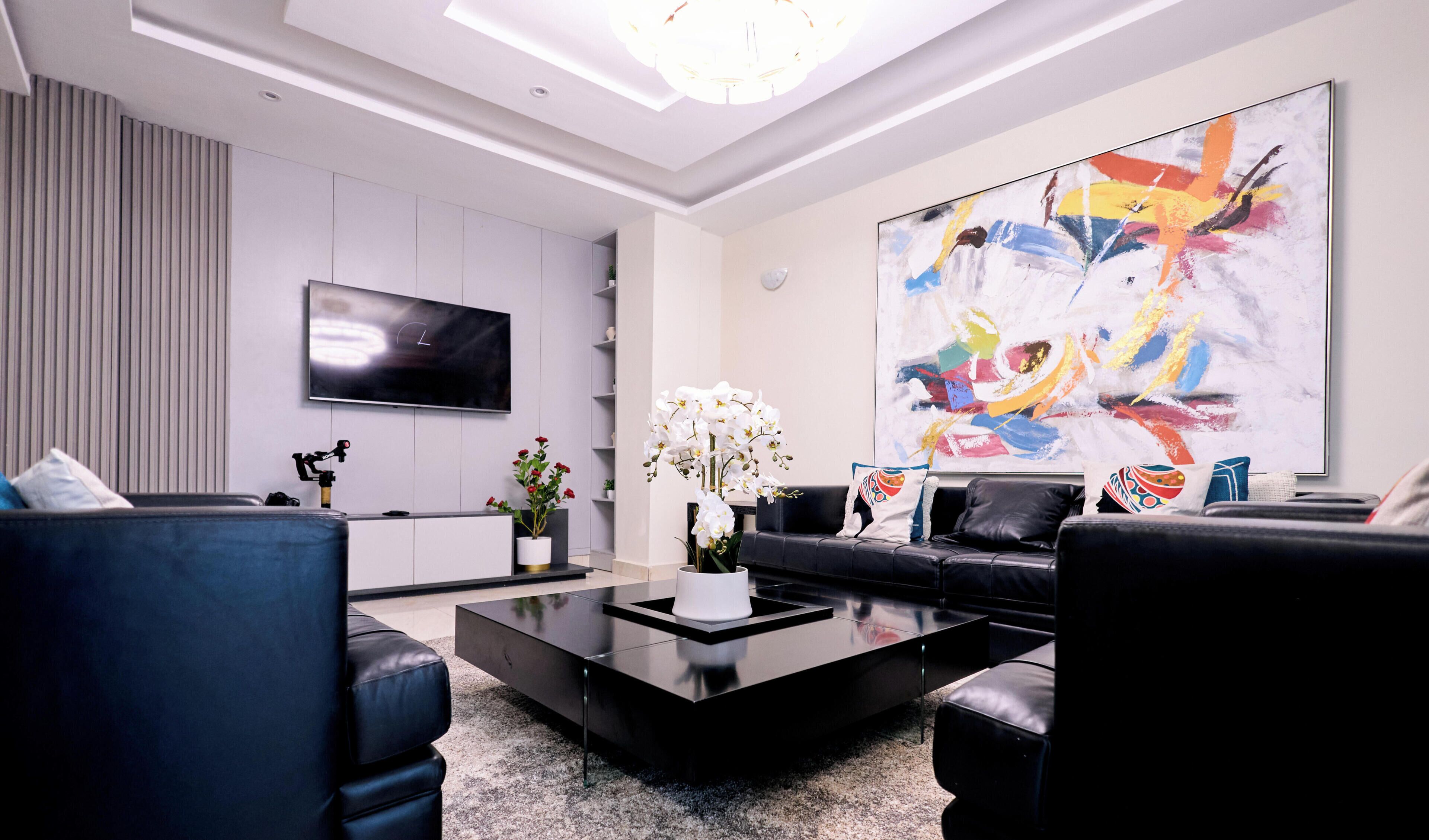A modern living room with a flat-screen TV, a large abstract painting, a coffee table, and two sofas.