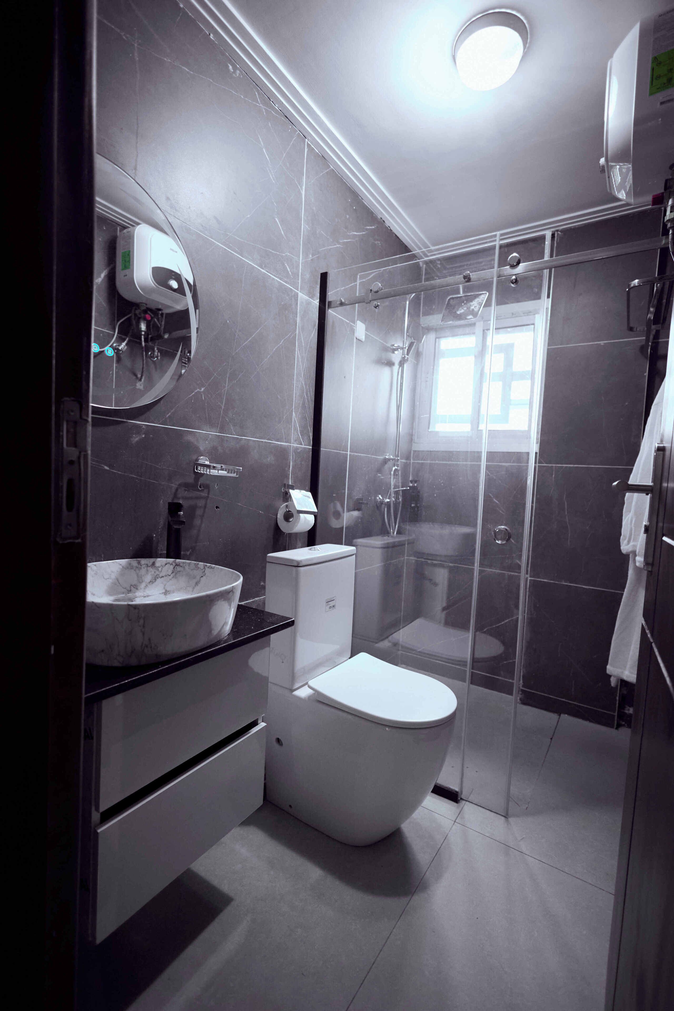 Un baño moderno con lavamanos, inodoro y ducha con mampara de vidrio de mármol.