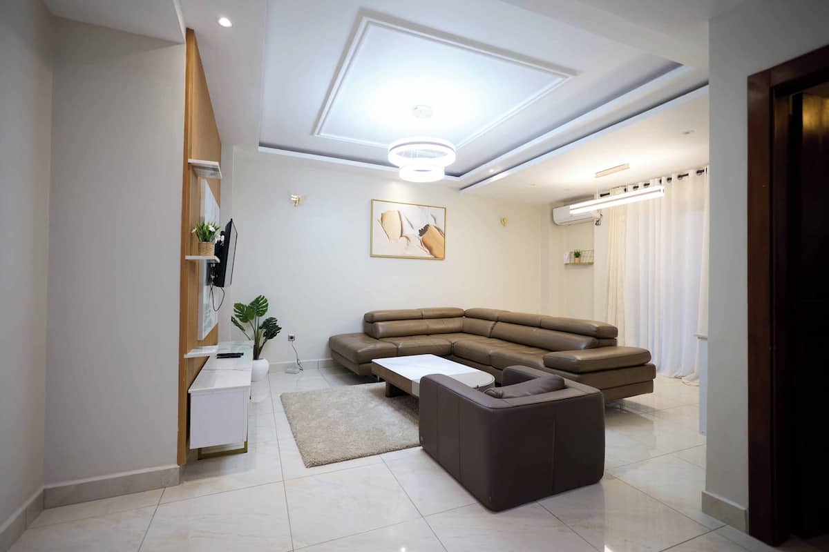 Una sala de estar moderna con un sofá seccional, una mesa de centro y una mesita auxiliar.