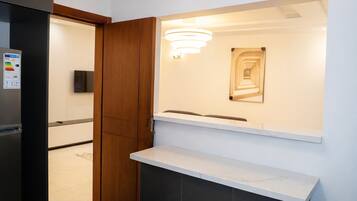 Una cocina moderna con refrigerador empotrado, un mueble de madera, una encimera blanca y un aplique de pared.