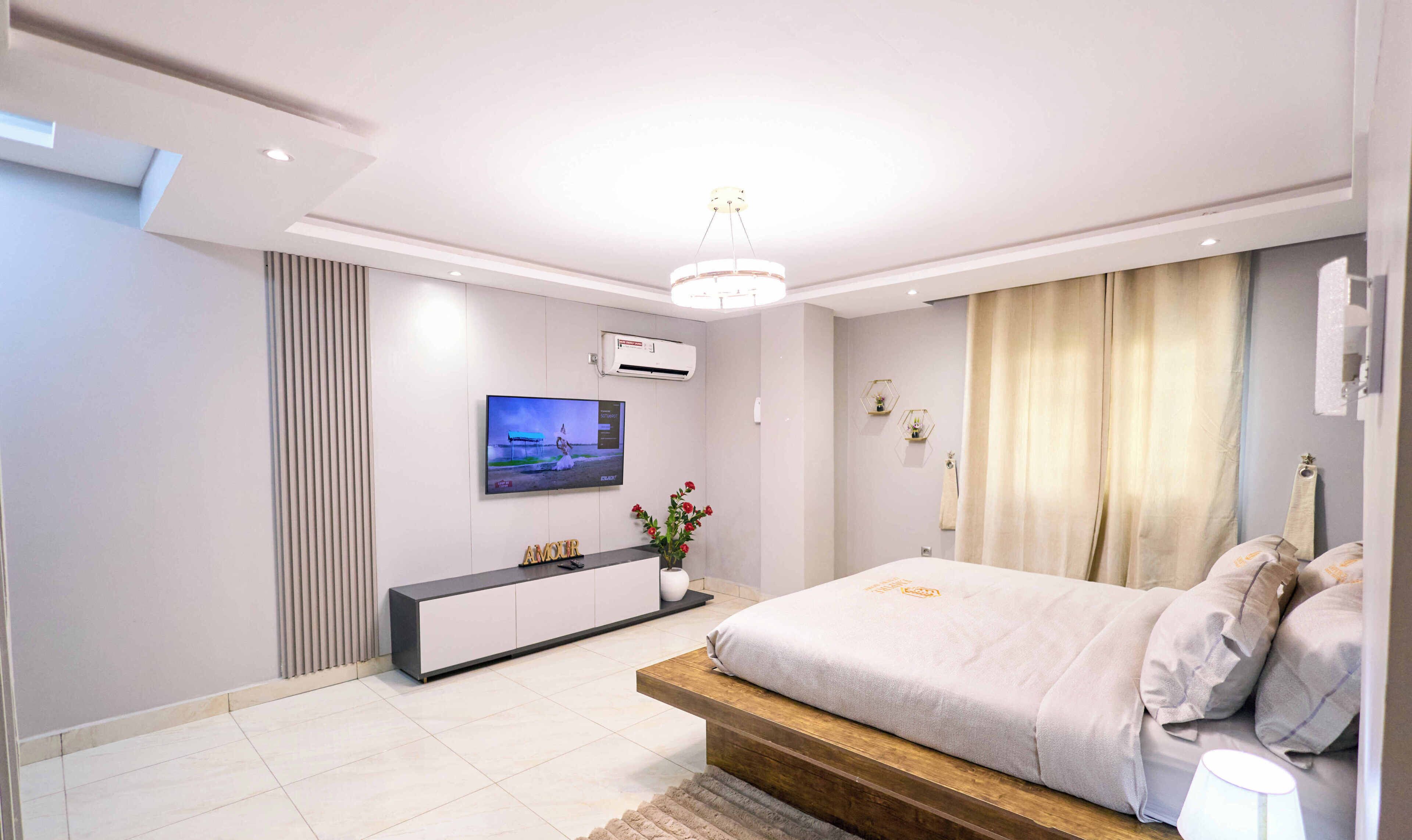Une chambre moderne avec un lit, une télévision, une console et une fenêtre avec des rideaux.