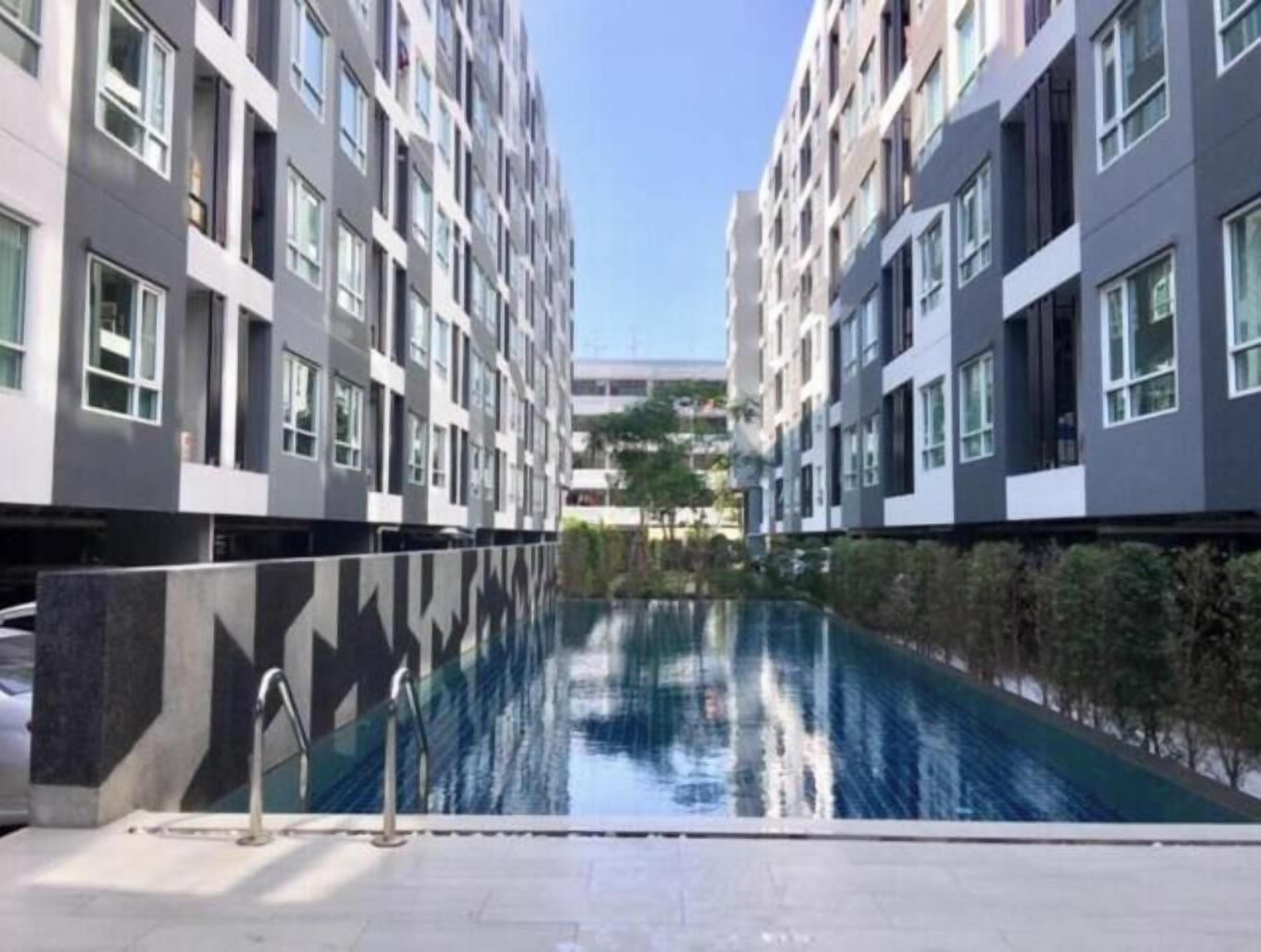 A modern building with a central pool, surrounded by greenery.