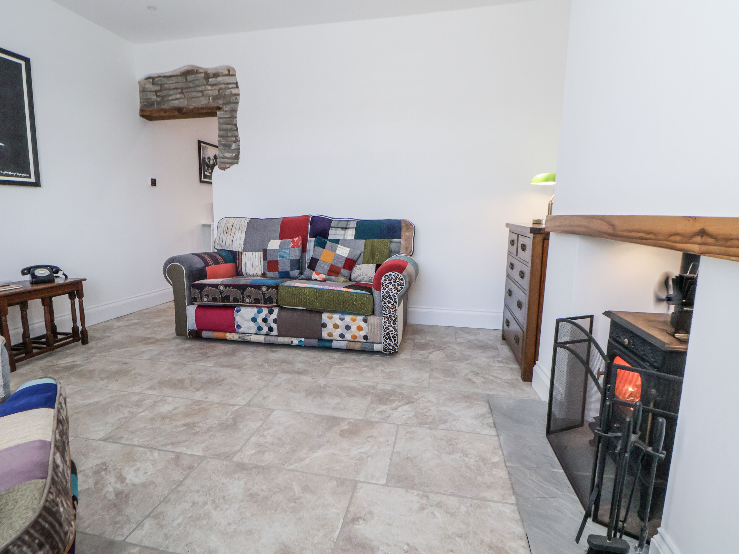 A living room with a multi-colored patchwork sofa, a fireplace, and a stone wall.
