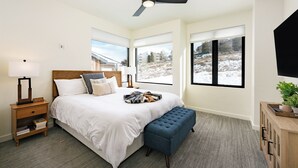 A bedroom with a bed, bedside table, nightstand, and a ceiling fan. - Base Camp Townhome #106 Slopeside 3 bedroom townhome, views, private balcony (Granby)