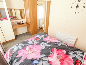 Ein Schlafzimmer mit Bett, Kleiderschrank, Spiegel und Heizkörper.
