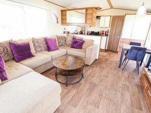 A living area with a sofa, a round coffee table, and a dining table with chairs. - Loopys Place - Pg178 (Skegness)