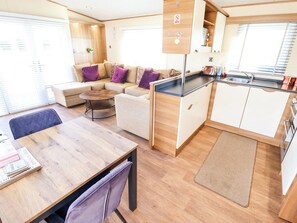 A compact living space with a sofa, a dining table, a kitchen area, and a small seating area. - Loopys Place - Pg178 (Skegness)