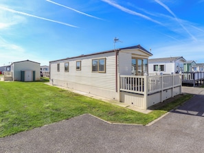 A mobile home with a fenced deck, a small attached garage, and a clear sky. - Loopys Place - Pg178 (Skegness)