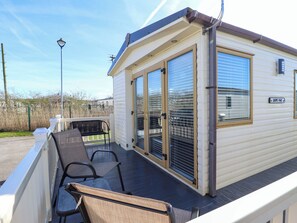 Ein kleines, eingeschossiges Mobilheim mit überdachter Terrasse, zwei Glastüren und einem Schild mit der Aufschrift 'LOOPS PLACE'.