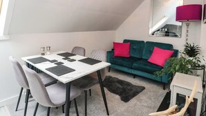 A dining area with a table and chairs, a sofa with cushions, a mirror, and a plant. - 3 Linshader (Isle of Lewis)
