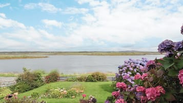 A landscaped garden with a variety of flowers and a spiral stone sculpture.
