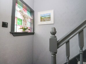 A staircase with a handrail, a wall-mounted light switch, a window with a plant, and a framed picture. - 3 Linshader (Isle of Lewis)