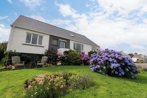 Ein zweistöckiges Haus mit einem Garten davor.