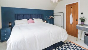 A bedroom with a bed, bedside table, nightstand, hanging light fixture, and a door. - 3 Linshader (Isle of Lewis)
