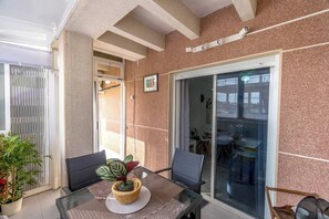 A balcony with a glass door leading to a dining area, a potted plant, and a woven basket on the table. - Penthouse in Central Torrevieja (Torrevieja)