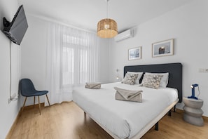 Ein Schlafzimmer mit Bett, Sessel, Fernseher und Lampe.
