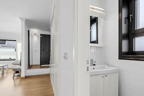 Ein modernes Badezimmer mit Waschbecken, Spiegel und Tür in dunkler Farbe.