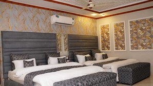 A hotel room with a large bed, a ceiling fan, an air conditioning unit, and decorative wall art. - Hotel Grand Orchard (Lahore)
