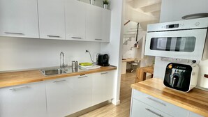 Una cocina moderna con armarios blancos, encimeras de madera, horno empotrado y cafetera.