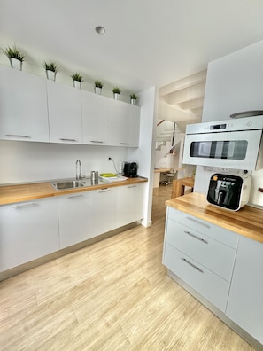 A modern kitchen with white cabinets, wooden countertops, a built-in oven, and a coffee machine. - Casahost Dolce Vita Pool (Costa Teguise)