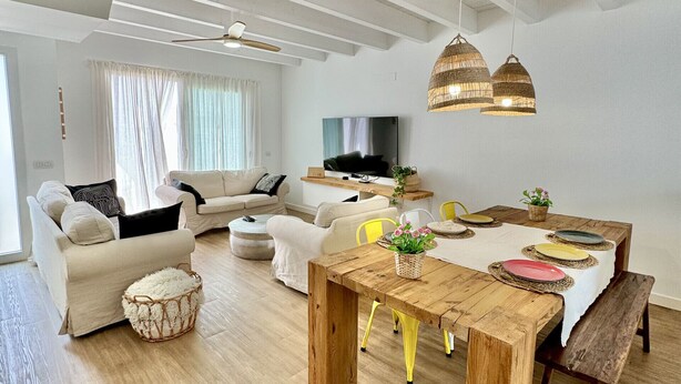 Amplia sala de estar con mesa de comedor de madera, sofás y televisor.